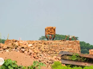 A man is carrying a lot of bricks on his head in the south of Bangladesh